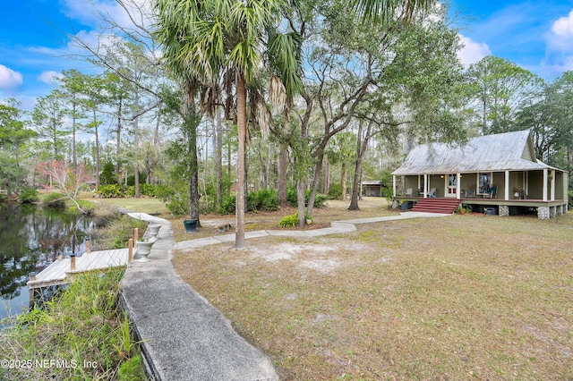 view of yard with covered porch, a dock, and a water view