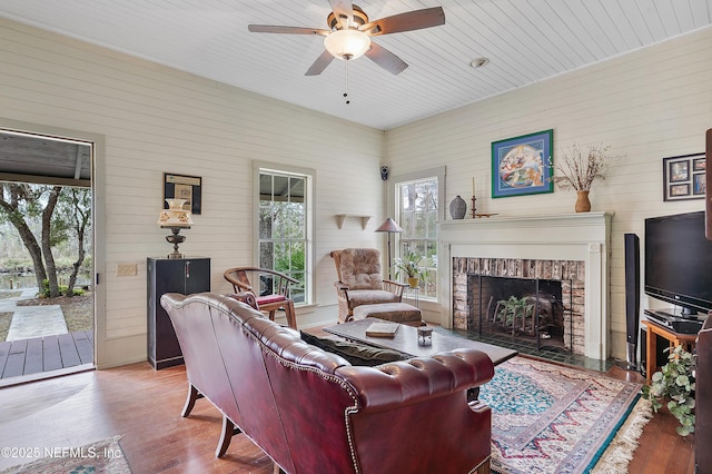 living room featuring a ceiling fan, wooden ceiling, a fireplace, and wood finished floors