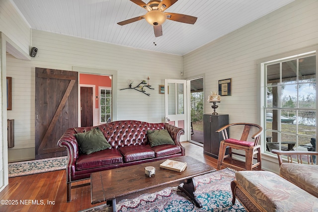 living room featuring ceiling fan, wood finished floors, a wealth of natural light, and wooden walls