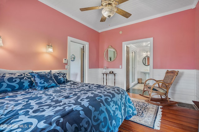 bedroom featuring visible vents, connected bathroom, wainscoting, ornamental molding, and wood finished floors