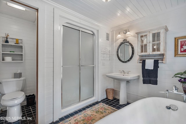 bathroom with crown molding, toilet, a stall shower, a freestanding tub, and tile patterned floors