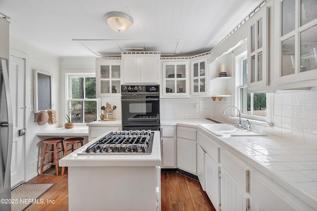 kitchen with tile countertops, a wealth of natural light, stainless steel gas cooktop, and a sink