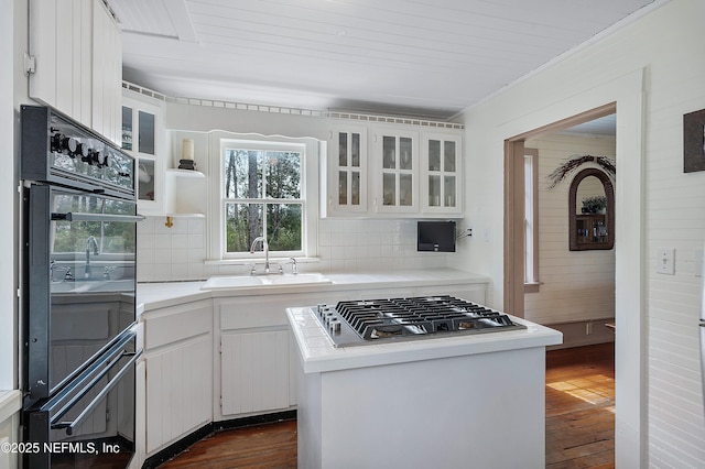 kitchen with dark wood-style floors, stainless steel gas cooktop, light countertops, and a sink