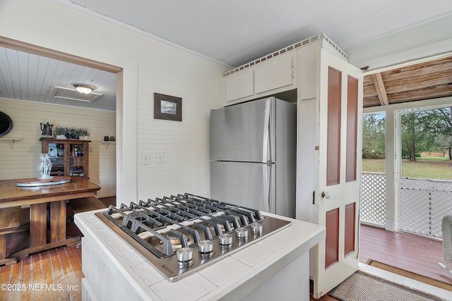 kitchen featuring light wood-style flooring, appliances with stainless steel finishes, white cabinets, and tile counters