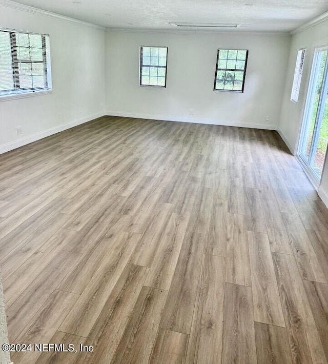 spare room featuring a textured ceiling, crown molding, and light wood-type flooring