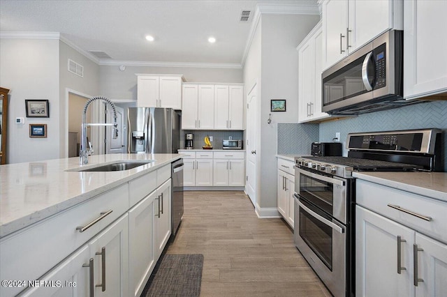 kitchen with light stone countertops, white cabinetry, sink, and appliances with stainless steel finishes