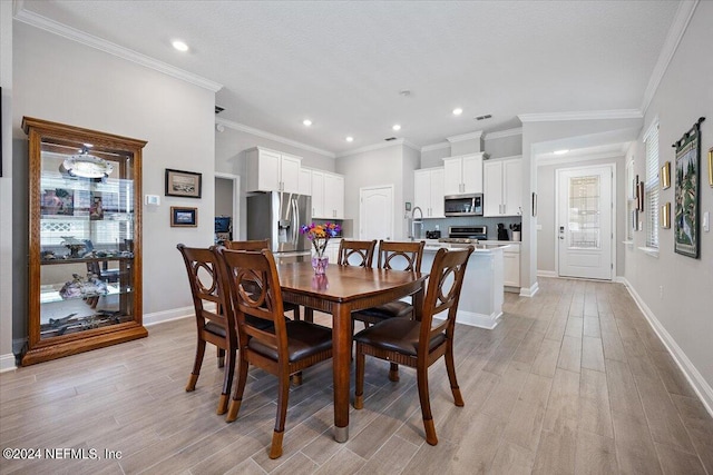 dining area with light hardwood / wood-style floors and crown molding