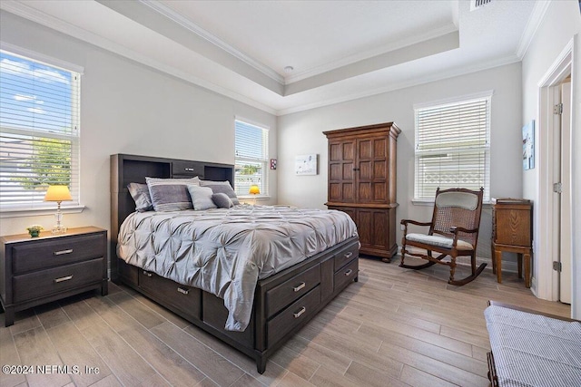 bedroom featuring crown molding, light hardwood / wood-style flooring, and a tray ceiling