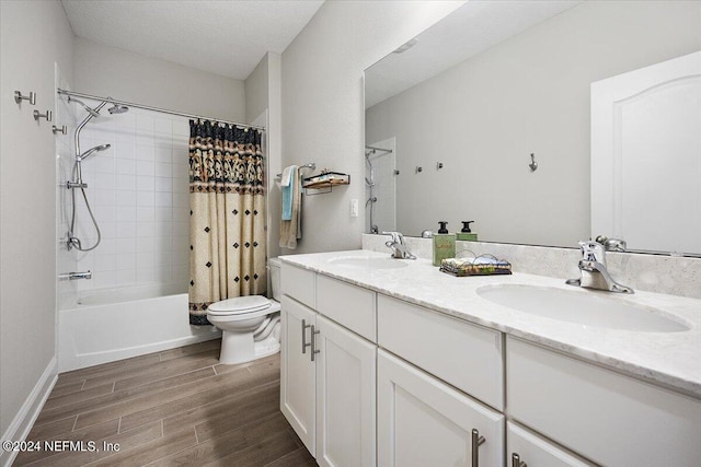 full bathroom with a textured ceiling, vanity, toilet, and shower / bath combo with shower curtain