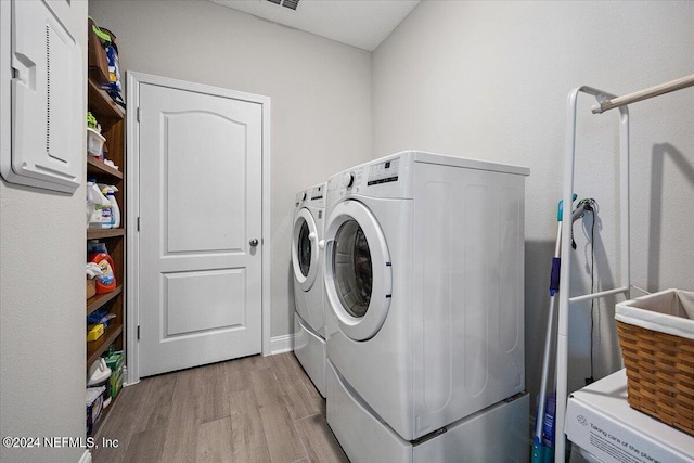 laundry area with washer and dryer and light hardwood / wood-style floors