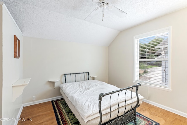 bedroom with wood-type flooring, lofted ceiling, a textured ceiling, and ceiling fan