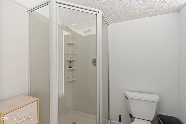 bathroom featuring walk in shower, toilet, and a textured ceiling