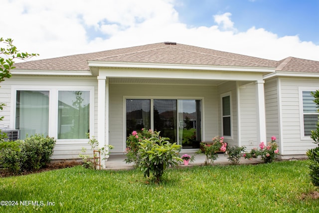 rear view of property featuring a lawn and covered porch