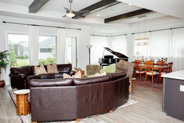 living room with beamed ceiling, ceiling fan with notable chandelier, and light wood-type flooring