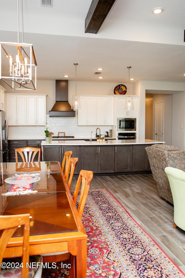 dining room with hardwood / wood-style floors, beam ceiling, sink, and a chandelier