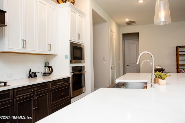 kitchen with oven, sink, built in microwave, tasteful backsplash, and white cabinetry