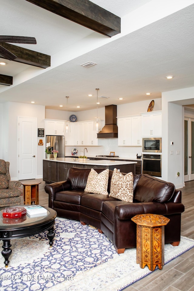 living room with beamed ceiling, light hardwood / wood-style floors, and sink