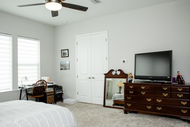 bedroom with ceiling fan, light colored carpet, and a closet