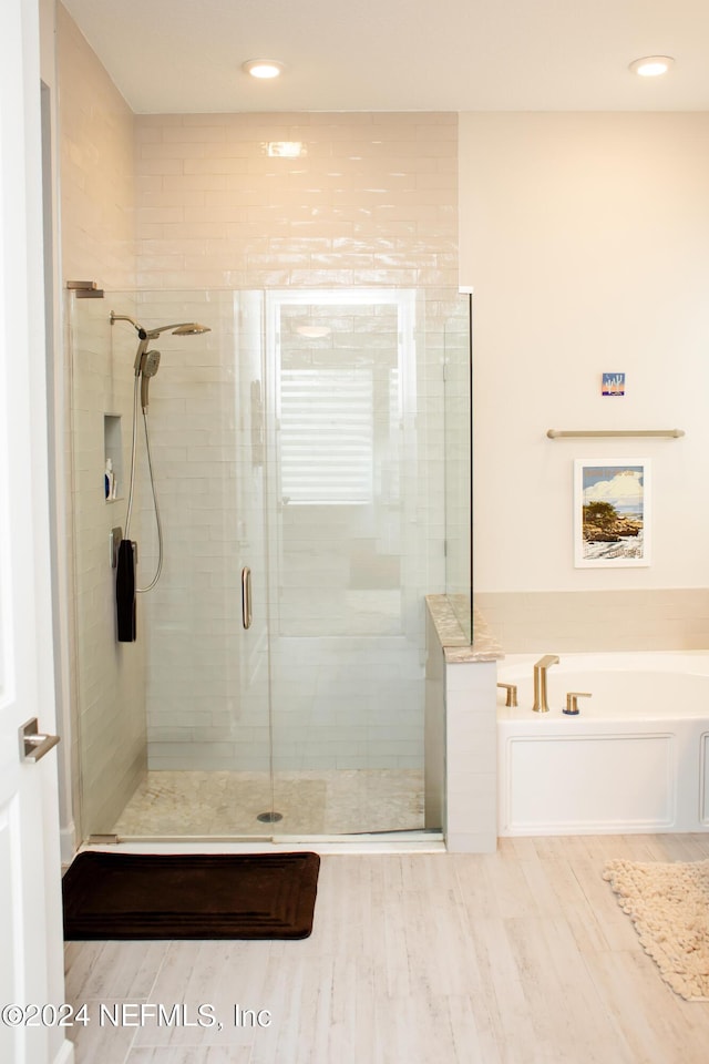 bathroom with hardwood / wood-style flooring and separate shower and tub