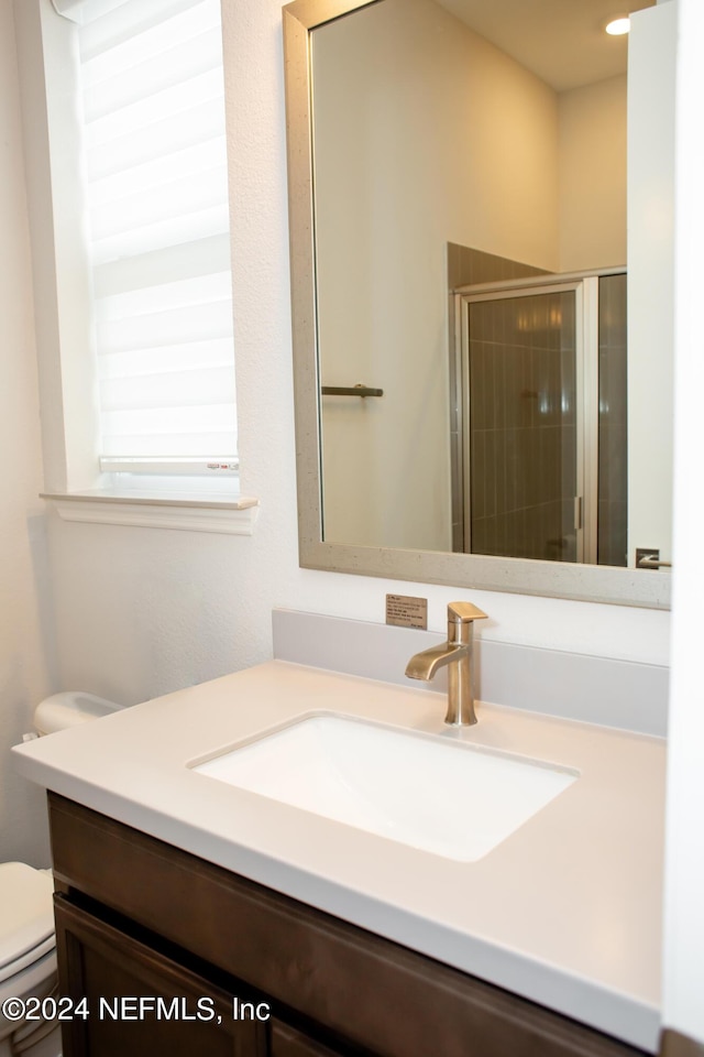 bathroom with vanity, a shower with shower door, and toilet