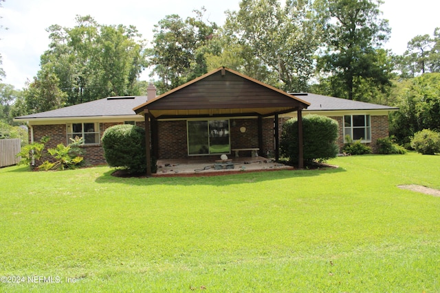 rear view of property featuring brick siding, a chimney, a lawn, a patio area, and fence