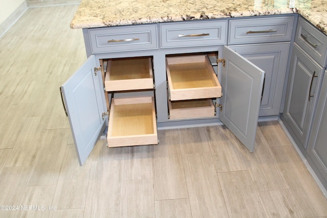 details featuring wood tiled floor, light stone countertops, and gray cabinetry