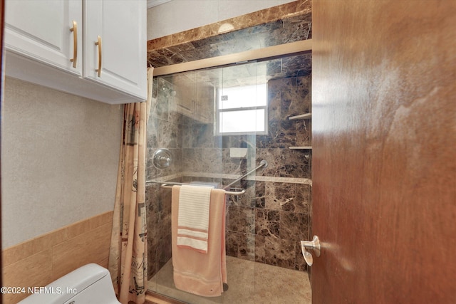 bathroom featuring a tile shower, tile walls, and toilet