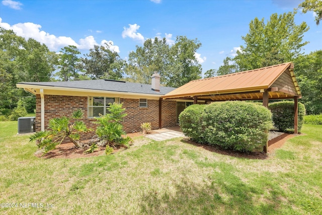 rear view of property featuring a gazebo, brick siding, a lawn, and a chimney