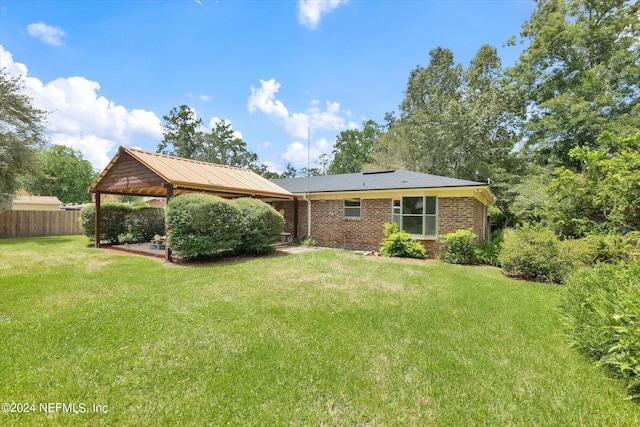 rear view of property featuring a yard, fence, and brick siding