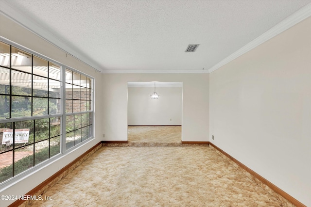 carpeted spare room with visible vents, crown molding, a textured ceiling, and baseboards