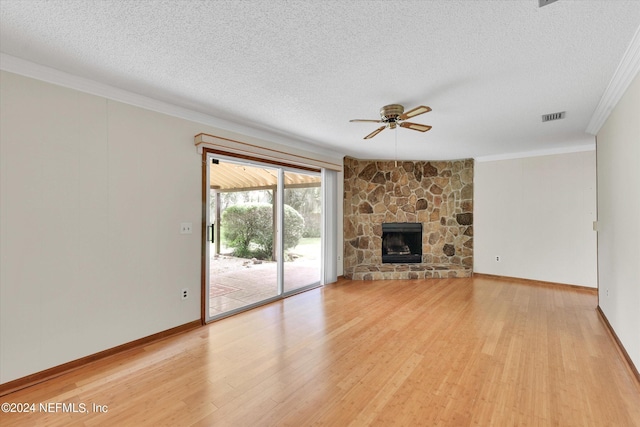 unfurnished living room with visible vents, ornamental molding, a textured ceiling, a stone fireplace, and light wood-type flooring