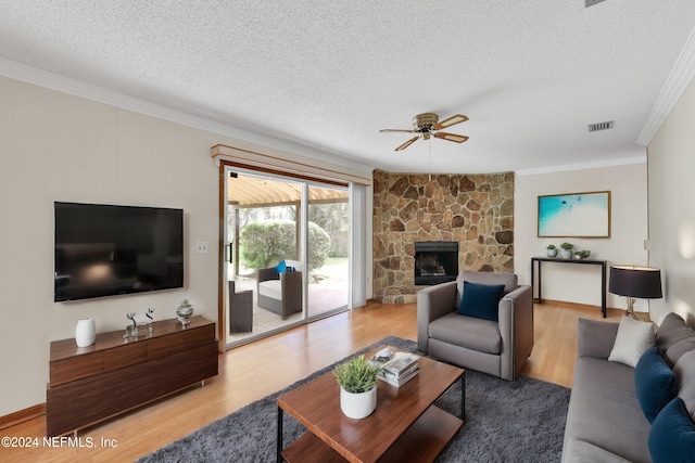 living area with ornamental molding, a fireplace, visible vents, and light wood-style floors