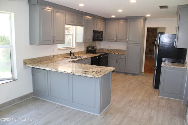 kitchen with black microwave, range with electric stovetop, a sink, and gray cabinetry