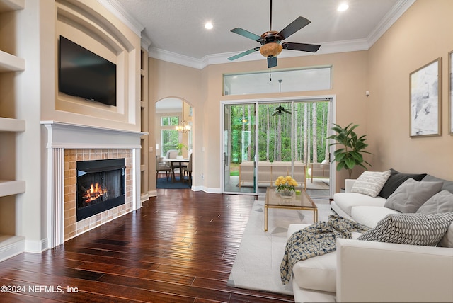 living room with dark hardwood / wood-style floors, ceiling fan, ornamental molding, and a tiled fireplace