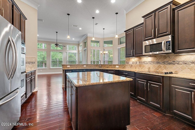 kitchen featuring backsplash, kitchen peninsula, decorative light fixtures, a kitchen island, and appliances with stainless steel finishes