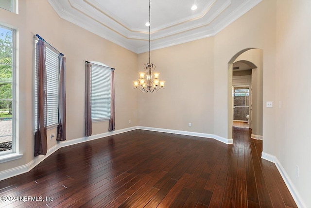 spare room featuring ornamental molding, dark hardwood / wood-style floors, a healthy amount of sunlight, and a notable chandelier