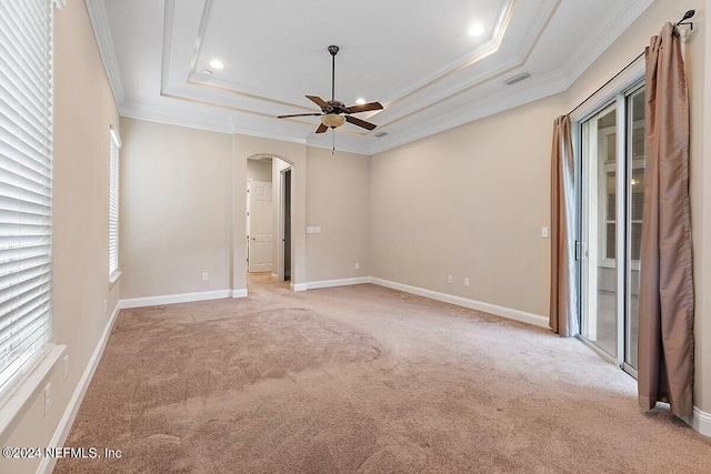 unfurnished room with a raised ceiling, ceiling fan, crown molding, and light carpet