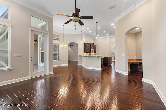 unfurnished living room with ceiling fan with notable chandelier, dark hardwood / wood-style flooring, ornamental molding, and a towering ceiling