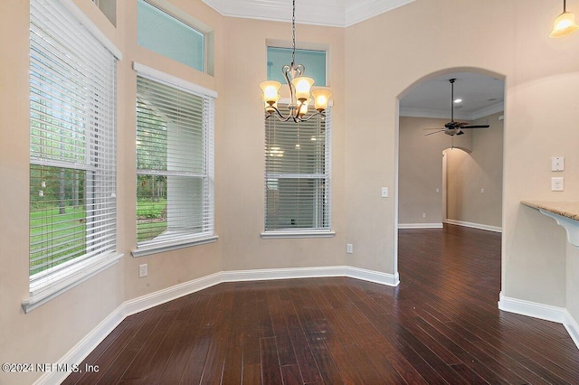 unfurnished dining area with ceiling fan with notable chandelier, a healthy amount of sunlight, ornamental molding, and dark wood-type flooring