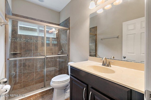 bathroom featuring tile patterned flooring, a shower with door, vanity, and toilet