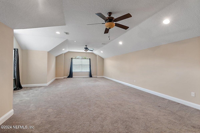 additional living space featuring ceiling fan, light colored carpet, lofted ceiling, and a textured ceiling