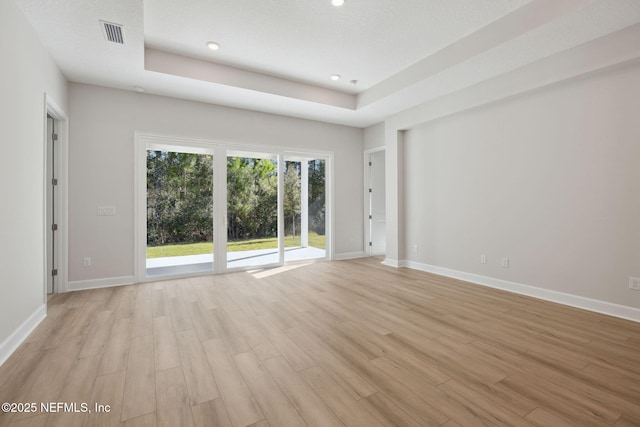 empty room featuring a raised ceiling and light wood-type flooring