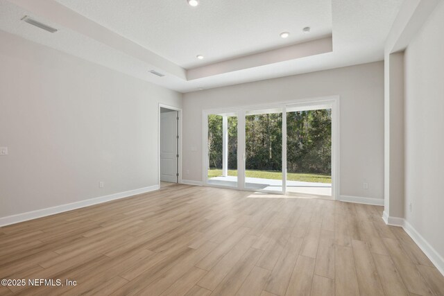 unfurnished room featuring a raised ceiling and light wood-type flooring