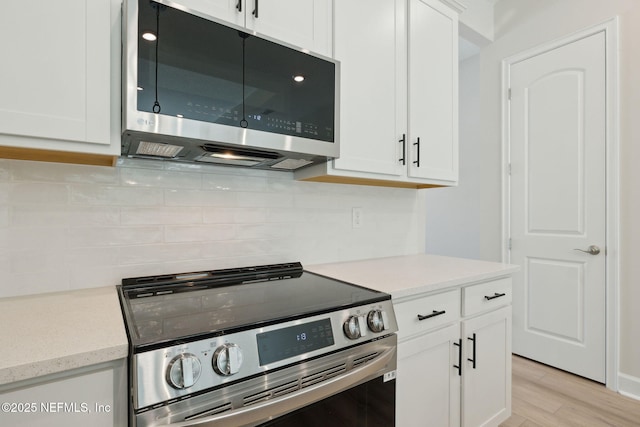 kitchen featuring white cabinets, decorative backsplash, light hardwood / wood-style floors, and stainless steel appliances