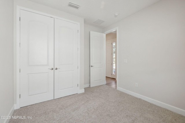 unfurnished bedroom with light colored carpet and a closet