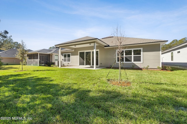 rear view of house featuring a lawn, a sunroom, and a patio area