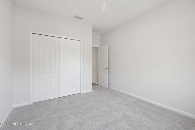 unfurnished bedroom with a closet and light colored carpet