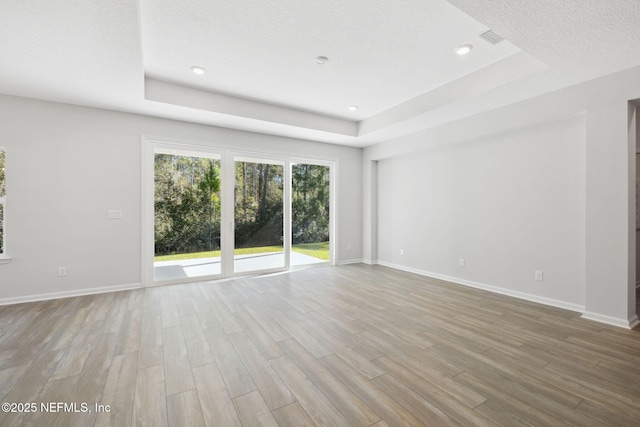 spare room featuring a raised ceiling and light hardwood / wood-style floors