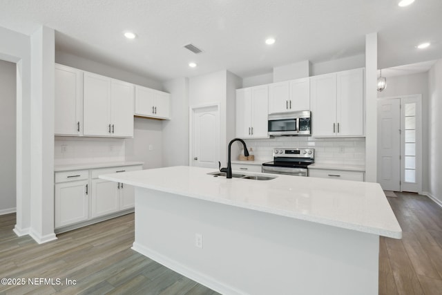 kitchen featuring a center island with sink, white cabinetry, sink, and appliances with stainless steel finishes