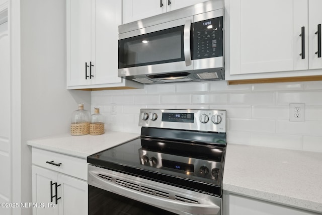 kitchen with appliances with stainless steel finishes, tasteful backsplash, white cabinetry, and light stone counters